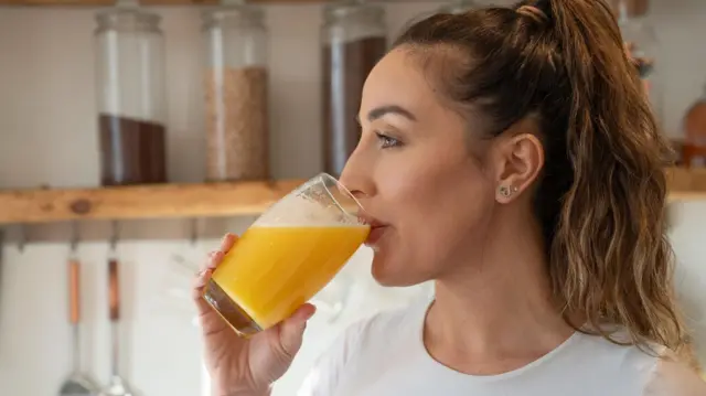 Mujer bebiendo un vaso de jugo de naranja fresco