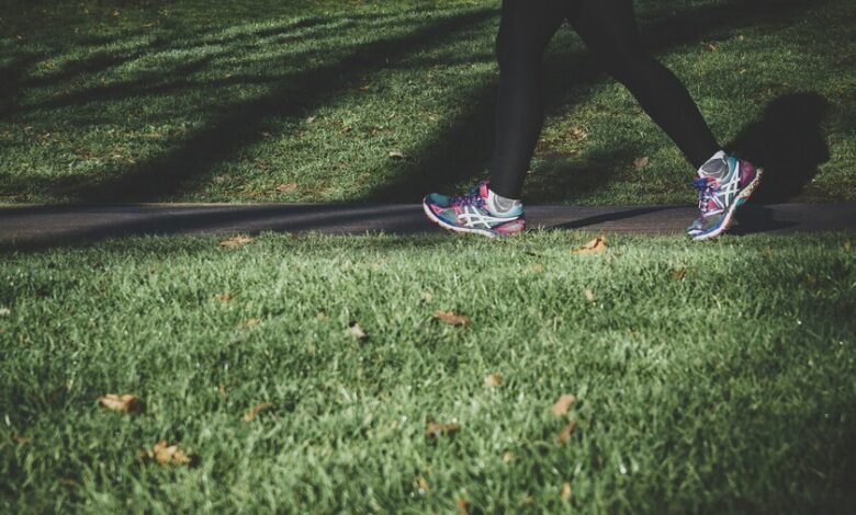 Persona caminando en un parque con un reloj de pulsera que muestra la velocidad y la distancia recorrida