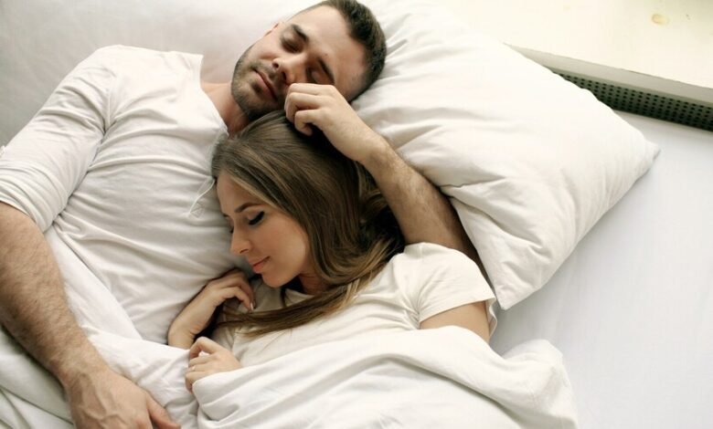 Pareja durmiendo en una cama con edredón