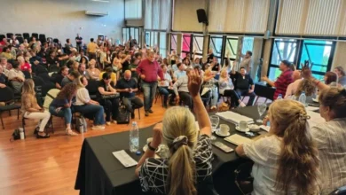 Docentes en asamblea, con carteles y banderas, protestando por sus derechos laborales