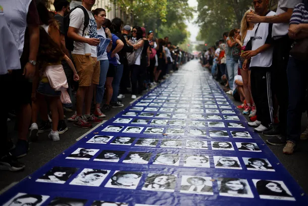 Imagen de una marcha en Plaza de Mayo con banderas y carteles en memoria de las víctimas de la dictadura