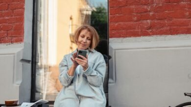 Mujer mayor sonriendo mientras usa su teléfono móvil