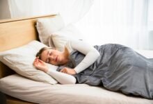 Persona durmiendo en una cama con una almohada y una manta