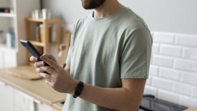 Un hombre con su teléfono inteligente en la mano, con una expresión de aburrimiento