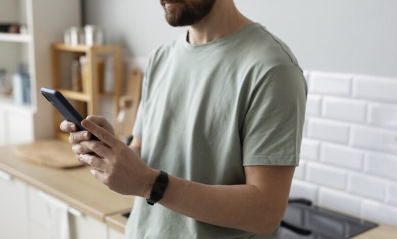 Un hombre con su teléfono inteligente en la mano, con una expresión de aburrimiento