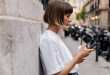 Persona sentada en un sofá con la cabeza entre las manos, rodeada de dispositivos electrónicos