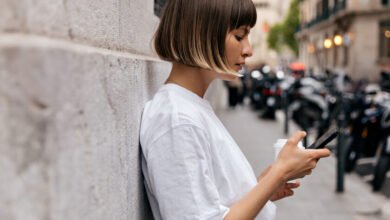 Persona sentada en un parque, mirando su teléfono con una expresión de ansiedad