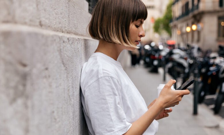 Persona sentada en un parque, mirando su teléfono con una expresión de ansiedad