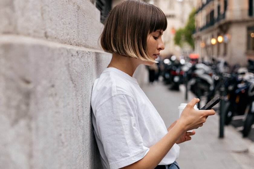 Persona sentada en un parque, mirando su teléfono con una expresión de ansiedad