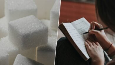 Una persona estudiando con un vaso de azúcar en la mesa
