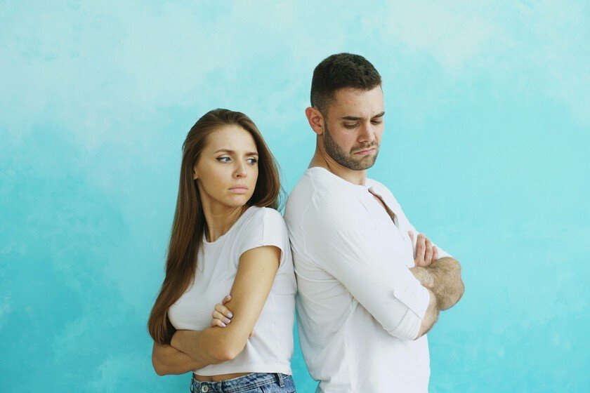 una persona sentada en una silla, con una expresión de estrés en su rostro, rodeada de personas que la están criticando