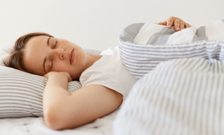 Persona durmiendo en una cama con una almohada y una manta