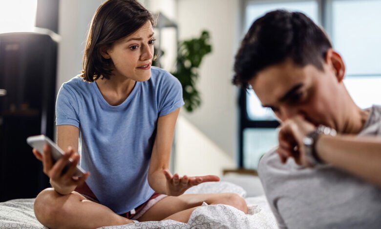 Imagen de una pareja con una pantalla de teléfono móvil en el medio, simbolizando la infidelidad en la era digital