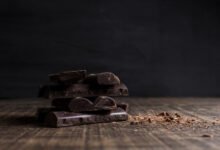 Imagen de un trozo de chocolate negro sobre una mesa de madera oscura