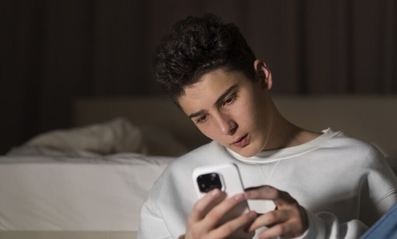 Imagen de un joven con una expresión de preocupación mientras usa su teléfono móvil