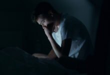 Persona despierta a las 2 de la madrugada, sentada en la cama con una expresión de confusión