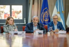 Imagen de una persona sostiene una bombilla de bajo consumo con un fondo de paneles solares