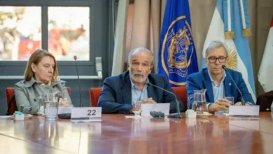 Imagen de una persona sostiene una bombilla de bajo consumo con un fondo de paneles solares