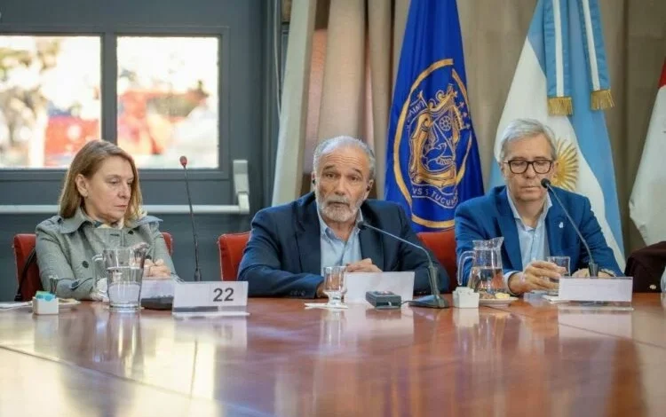 Imagen de una persona sostiene una bombilla de bajo consumo con un fondo de paneles solares