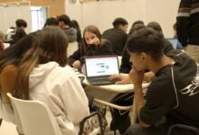 Estudiantes trabajando en equipo con laptops y papel
