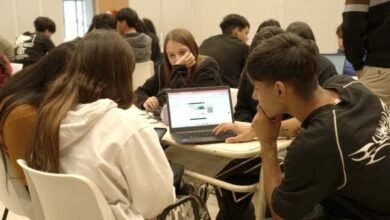 Estudiantes trabajando en equipo con laptops y papel