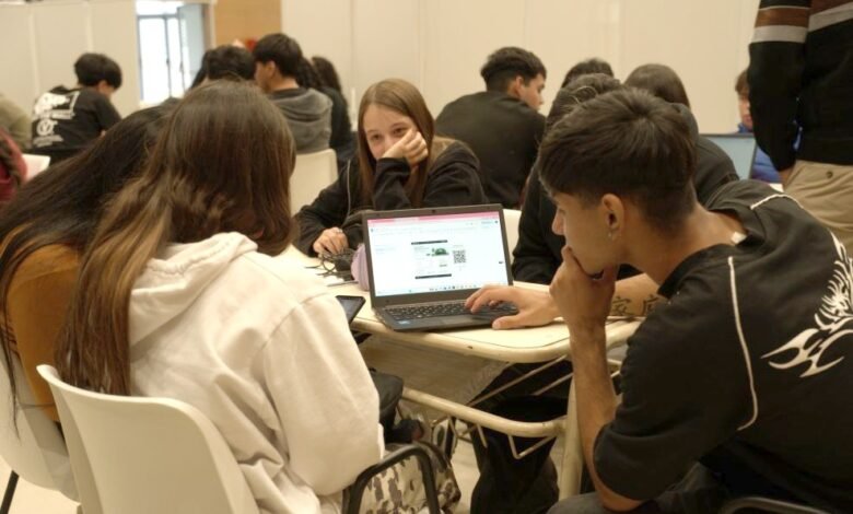 Estudiantes trabajando en equipo con laptops y papel