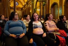 Imagen de una mujer embarazada sonriendo con un bebé en brazos