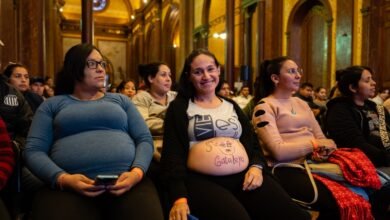Imagen de una mujer embarazada sonriendo con un bebé en brazos