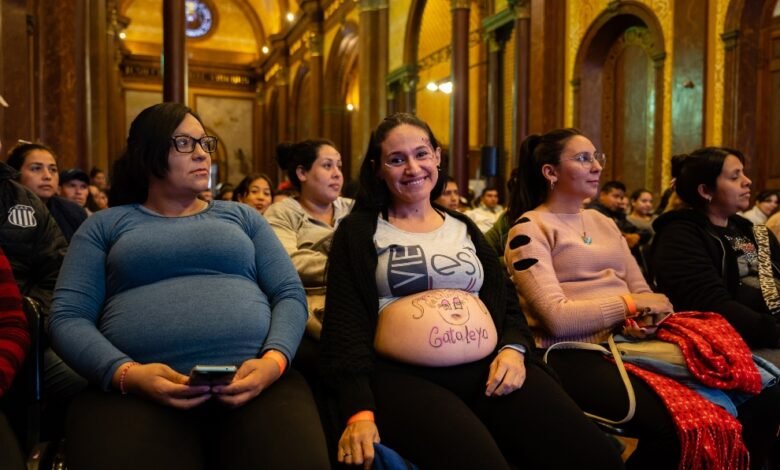 Imagen de una mujer embarazada sonriendo con un bebé en brazos