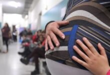Mujer embarazada sonriente con su bebé en brazos