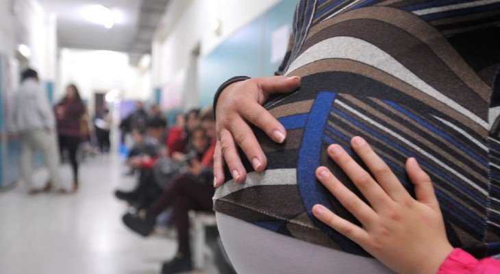 Mujer embarazada sonriente con su bebé en brazos