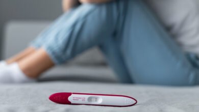 Imagen de una pareja sonriente con un perro, rodeados de elementos relacionados con la fertilidad y la salud