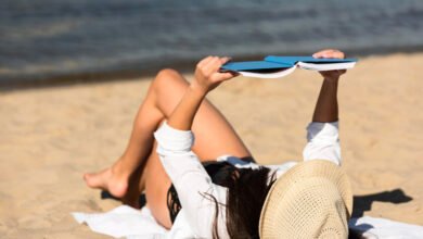 Persona sentada en una playa, con el móvil en la mano y una expresión de cansancio en el rostro.