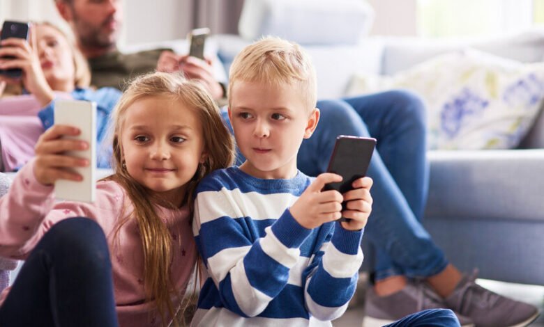 Niño leyendo un libro con un teléfono móvil al lado