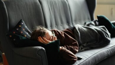 Persona durmiendo en un sofá, con un reloj en la mesa de café