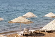 Persona bajo una sombrilla de playa en la costa