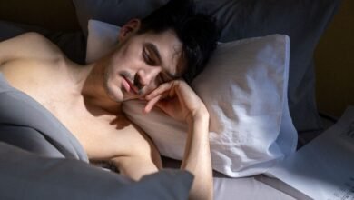 Persona durmiendo con una ventana abierta y un ventilador encendido