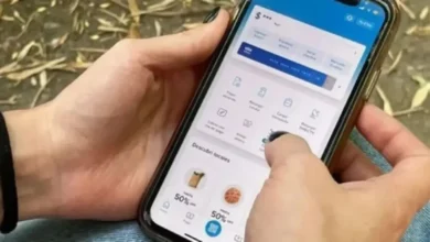 Imagen de una persona usando un teléfono móvil con una aplicación bancaria, con un fondo de cifras y códigos de seguridad