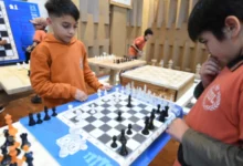 Niños jugando ajedrez en una mesa con tableros y piezas de ajedrez