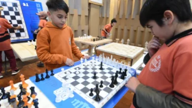 Niños jugando ajedrez en una mesa con tableros y piezas de ajedrez