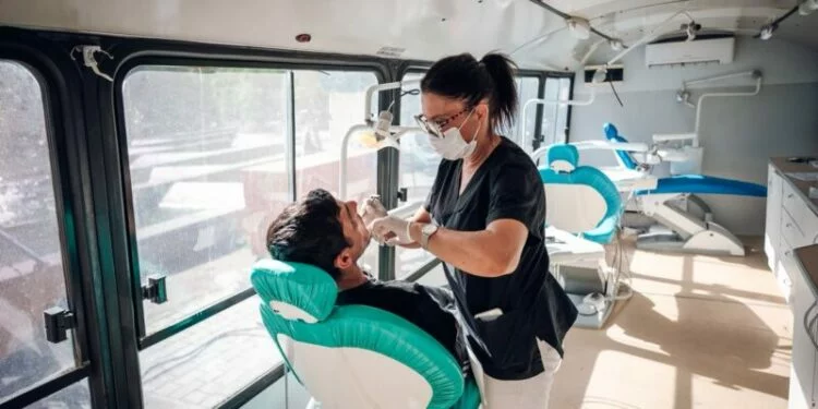 Persona realizando un autoexamen bucal frente al espejo