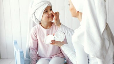 Adolescente aplicándose crema facial mientras mira su móvil, ilustrando la tendencia del skincare entre jóvenes