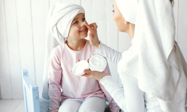 Adolescente aplicándose crema facial mientras mira su móvil, ilustrando la tendencia del skincare entre jóvenes