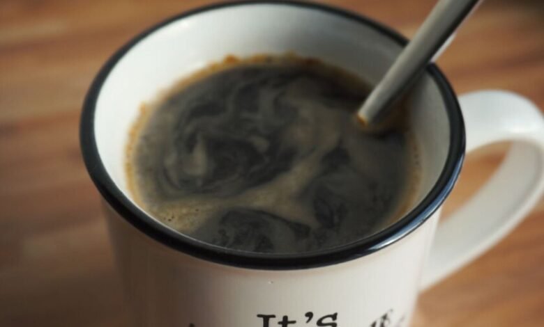 Taza de café humeante sobre una mesa de madera