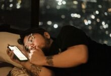 Persona usando móvil en la cama con luz azul que afecta el sueño
