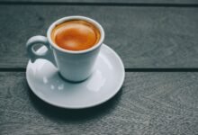 Taza de café humeante sobre una mesa de madera