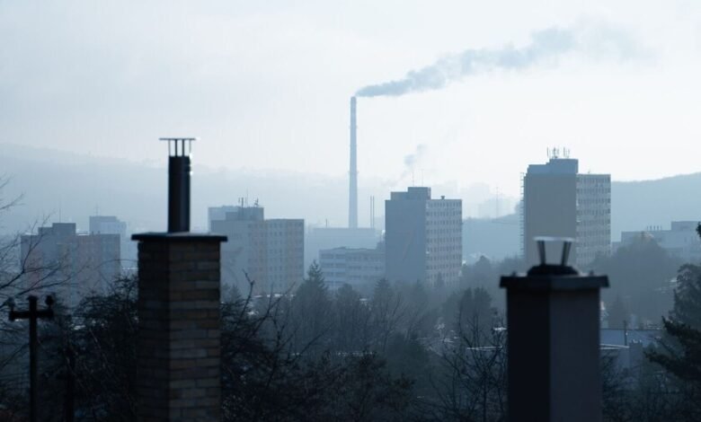Vista aérea de una ciudad con smog y una sonrisa superpuesta que simboliza la contaminación del aire que afecta la salud dental