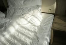 Habitación con cama deshecha y persianas abiertas para ventilar